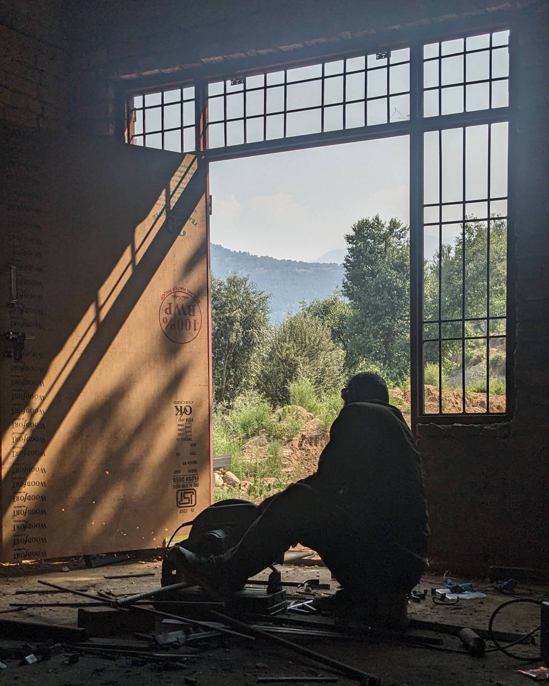 Worker welding racks, Chenab Valley visible